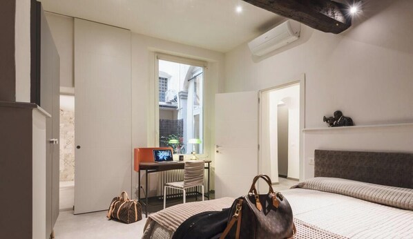 Ein Hotelzimmer mit Bett, Schreibtisch, Stuhl und Fenster.
