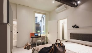 Habitación de hotel con cama, escritorio, silla y ventana.