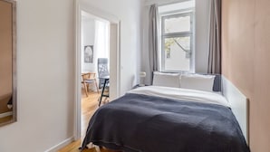 A bedroom with a bed, a window with curtains, a chair, and a desk. - Blueground | Mariahilf, fully furnished & ready (Vienna)
