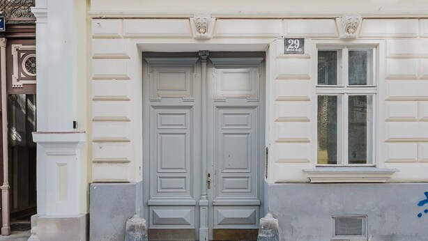 A double door with a number '29' above it, a window with a grid pattern, and a small vent on the wall. - Blueground | Mariahilf, fully furnished & ready (Vienna)