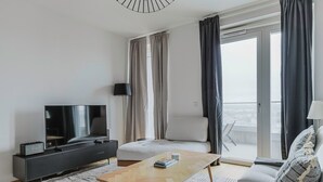 A modern living room with a flat-screen TV, a wooden coffee table, a sofa, and a balcony with curtains. - Blueground | Landstraße, pool, gym, sauna & a/c (Vienna)