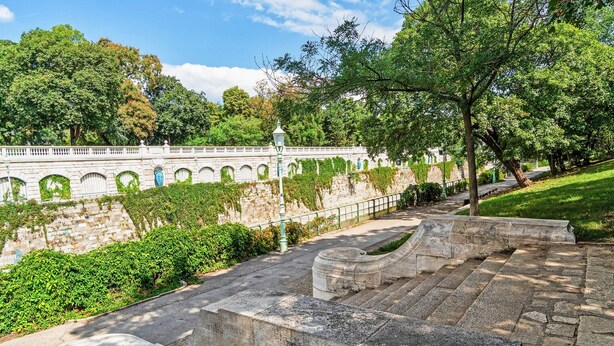 A stone staircase leading up to a white building with arched windows and a wall covered in greenery. - Blueground | Landstraße, pool, gym, sauna & a/c (Vienna)
