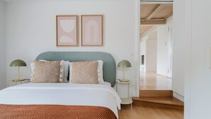 A bedroom with a bed, two bedside tables, a nightstand, a headboard, and a door leading to another room. - Blueground | Fluntern, private w/d, walk to market (Zurich)