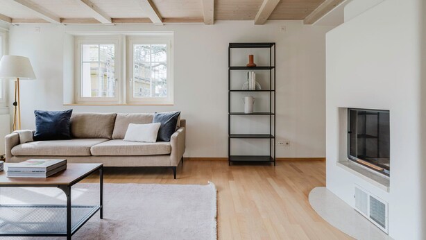 A living room with a sofa, a coffee table, a fireplace, and a bookshelf. - Blueground | Fluntern, private w/d, walk to market (Zurich)