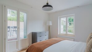 A bedroom with a bed, a dresser, a lamp, and a window. - Blueground | Fluntern, private w/d, walk to market (Zurich)