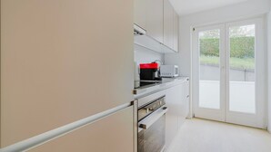 A modern kitchen with white cabinets, a black and red coffee maker, and a microwave.