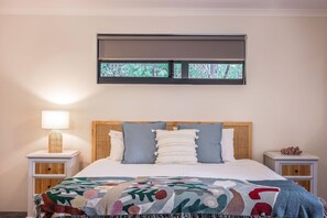A bedroom with a bed, a window with a view of trees, a bedside lamp, and a nightstand. - Peppermint Retreat - perfect rural getaway (Quindalup)
