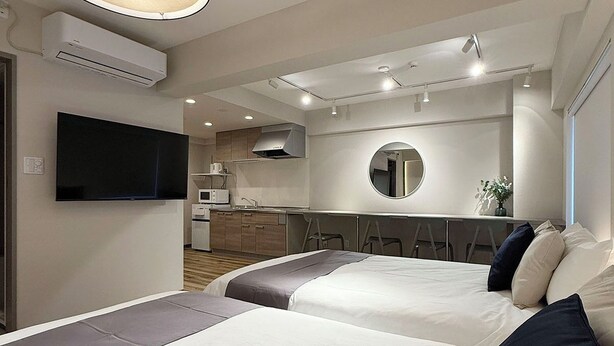 A modern hotel room with two beds, a kitchen area, and a TV. - Clio Matoba by b-hotel (Hiroshima)