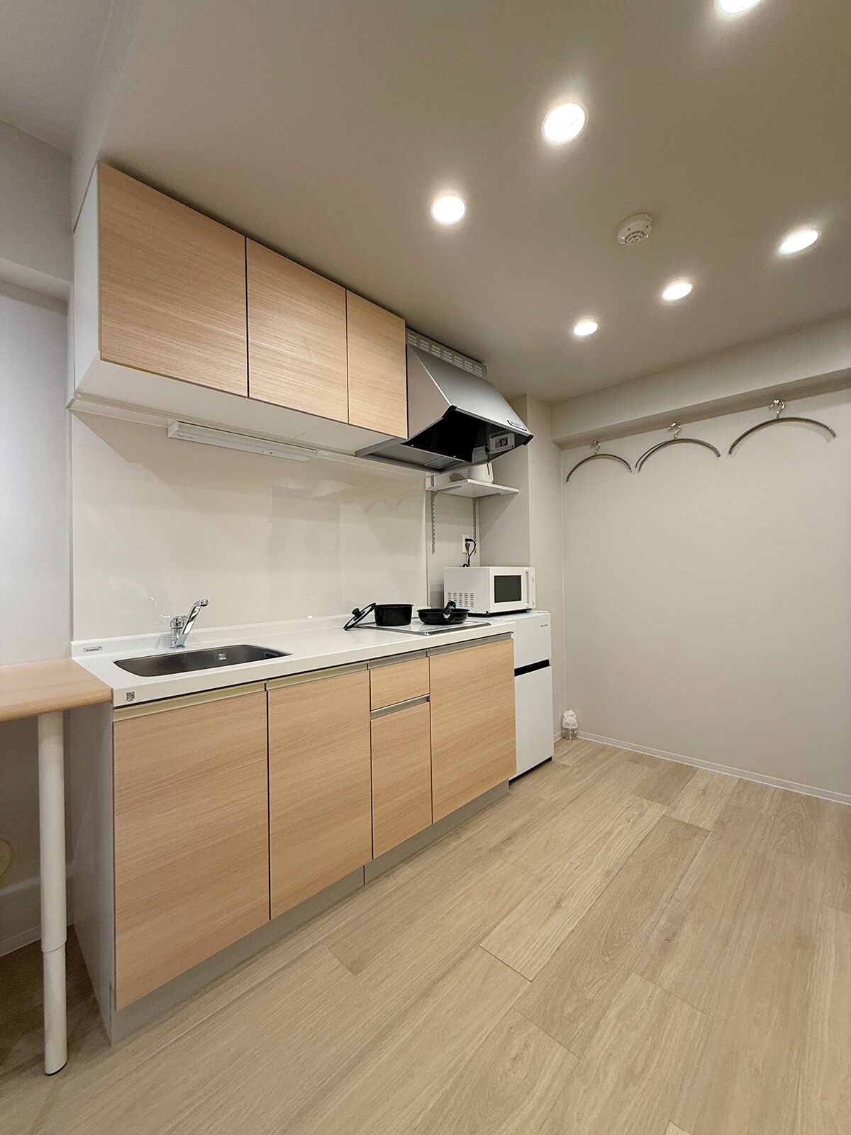 Een moderne keuken met houten kastjes, een spoelbak, een magnetron en een fornuis.