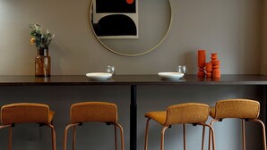 A modern dining area with a round mirror, a vase with flowers, and a bar with stools. - Clio Matoba by b-hotel (Hiroshima)