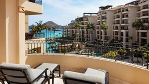 Un balcon avec deux fauteuils de relaxation, une piscine et une vue sur un bâtiment d’un complexe hôtelier.