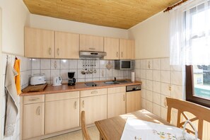 Une cuisine compacte avec des meubles en bois, un four à micro-ondes, une machine à café et un évier.