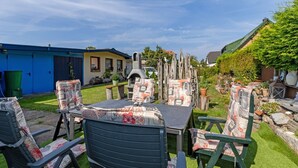 Eine Terrasss mit Tisch und Stühlen, einem Grill und einer Steinmauer.