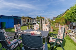 An outdoor patio with a table and chairs, a barbecue grill, and a stone wall. - Blumentraum Vacation Rental with 2 Bathrooms - Bright "Blumentraum" Vacation Rental in Kühlungsborn (Kühlungsborn)