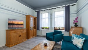 Ein modernes Wohnzimmer mit Fernseher, Holzkörperschränken, türkisfarbenen Sofas und einem Couchtisch.