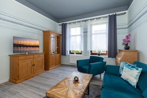 Un salon moderne avec un téléviseur, des meubles en bois, des canapés de couleur turquoise et une table basse.