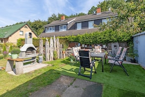 A backyard with a barbecue area, outdoor seating, and a house with a sloped roof. - Blumentraum Vacation Rental with 2 Bathrooms - Bright "Blumentraum" Vacation Rental in Kühlungsborn (Kühlungsborn)