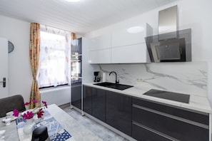Una cocina moderna con un lavamanos negro, armarios blancos y una campana extractora empotrada.