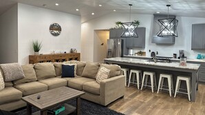 A modern kitchen with grey cabinets, a stainless steel refrigerator, and a marble island.