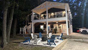 A two-story house with a covered patio area, outdoor seating, and a vehicle parked nearby.