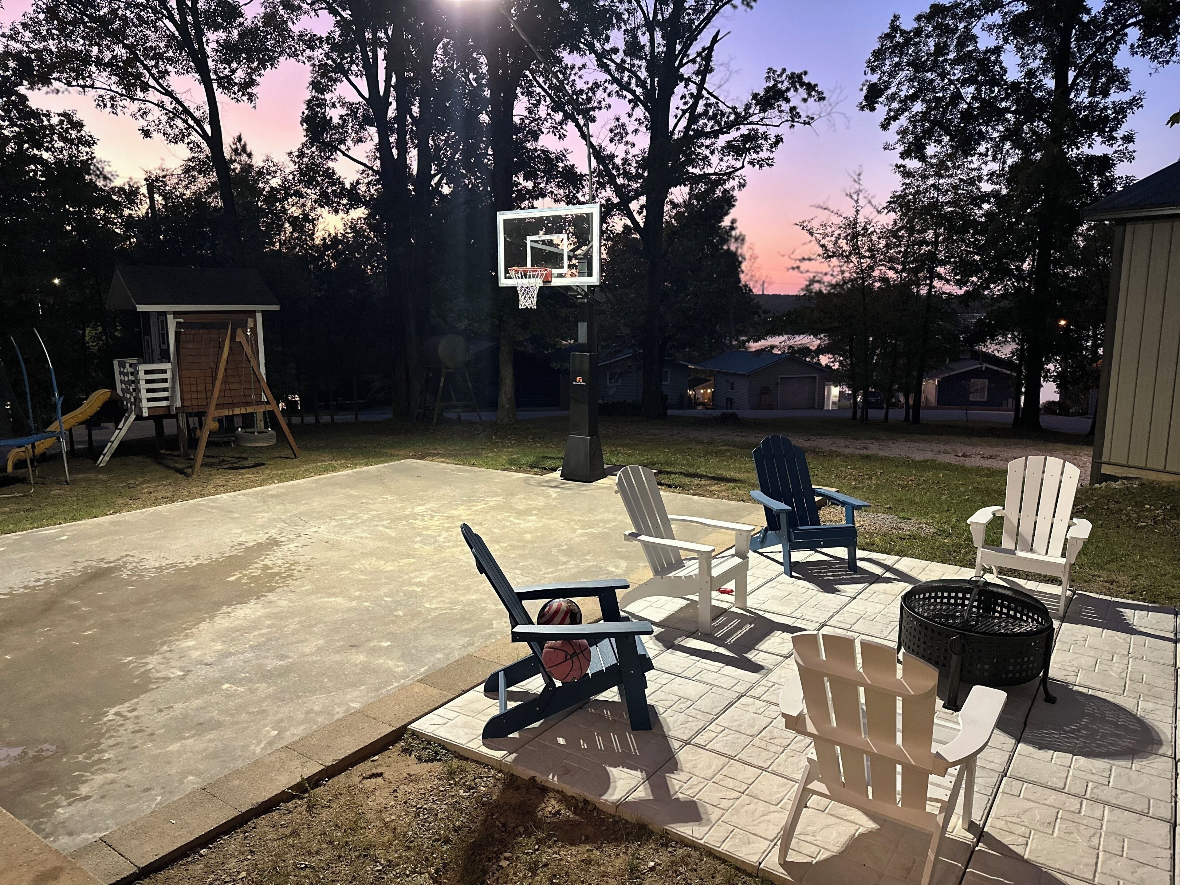 A backyard with a basketball hoop, outdoor seating, and a play area.