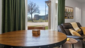 Una habitación con un ventanal grande, un sofá de cuero, una mesa de madera y un cuadro en la pared.
