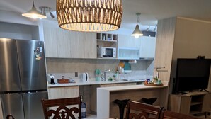 A dining area with a table set for four, surrounded by wooden chairs. A decorative runner spans the table, and a bowl of fruit is placed on the center. - Beautiful and comfortable department (Ñuñoa)