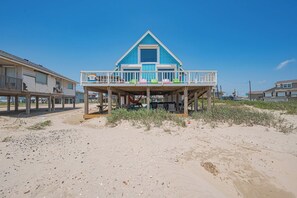 A beachfront house with a balcony and a small deck area.