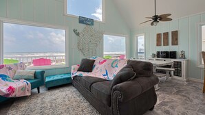 Sala de estar con vista al océano, ventilador de techo y un cartel que dice 'Jamaica Beach'.
