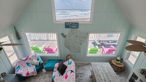 Acogedor dormitorio en ático con vista a la playa Jamaica, con cama elevada, una mesita y una hamaca.