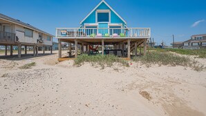 Una casa frente a la playa con balcón, terraza de madera y vista despejada al océano.