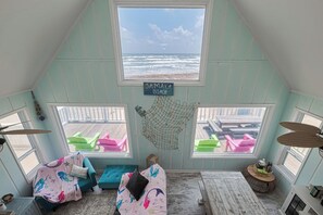 A room with a view of Jamaica Beach, featuring a loft-style ceiling, a hammock, and a wooden floor.