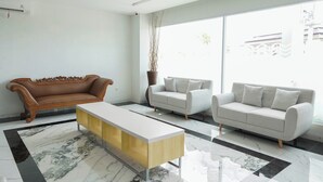 Una sala moderna con un sofá marrón, un sofá blanco y una mesa de centro blanca.