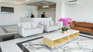 Un vestíbulo moderno con un mostrador de recepción, dos sofás, una mesita de café y un sofá marrón.