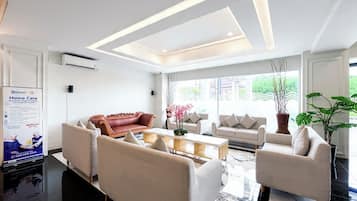 Un hall d’hôtel moderne avec un comptoir d’accueil, un espace salon et de grandes fenêtres.