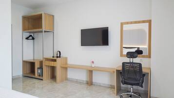 Una habitación de hotel moderna con un escritorio de madera, una silla de oficina negra, un televisor montado en la pared e iluminación integrada en un espejo.