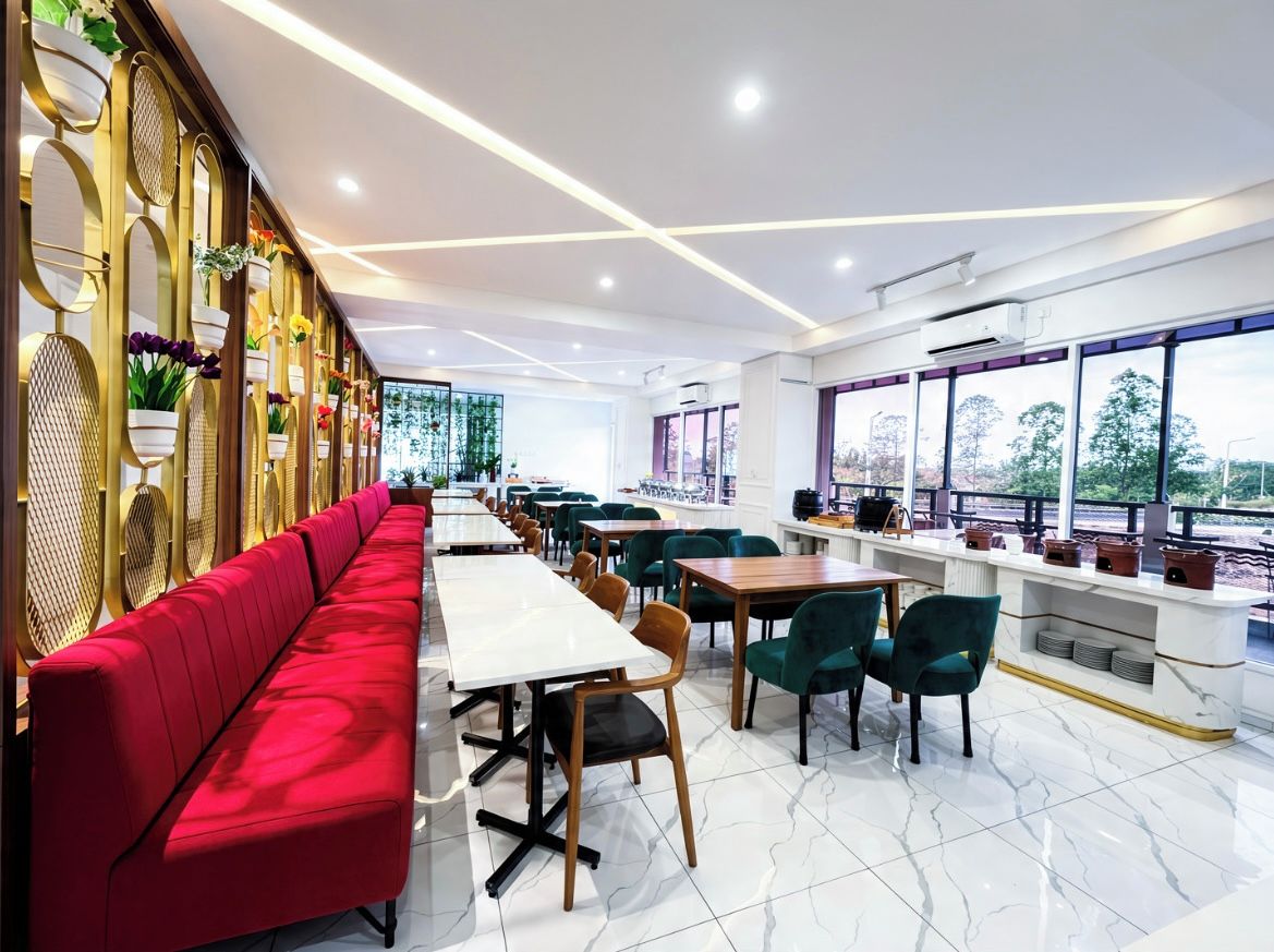 A modern restaurant with a long red bench, white tables, and green chairs.