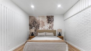 Une chambre à coucher comprenant un lit, deux tables de chevet et une œuvre d’art accrochée au mur.