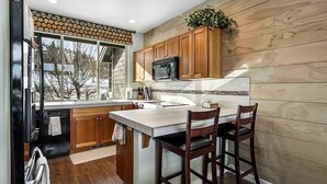 A modern kitchen with wooden cabinets, a large island, and a view of the outdoors. - Charming 3-bedroom townhome with WiFi, fitness room in peaceful Redmond (Redmond)