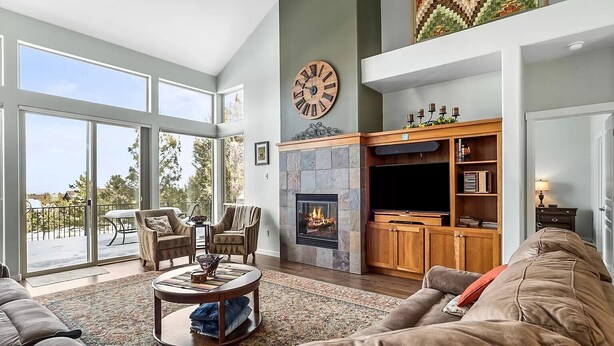 A spacious living room with a fireplace, a large clock, and a balcony with outdoor furniture. - Charming 3-bedroom townhome with WiFi, fitness room in peaceful Redmond (Redmond)