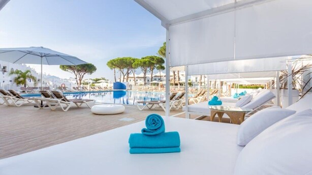 A poolside lounge area with sun loungers, umbrellas, and a view of the pool and trees. - Modern duplex 6303 - great facilities onsite (Marbella)