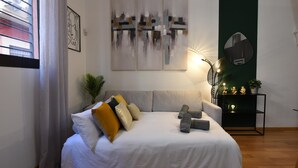 Une chambre à coucher moderne avec un lit, une table de chevet agrémentée d’objets décoratifs et des œuvres d’art abstraites au mur.