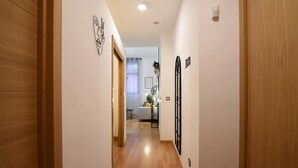 Un couloir avec un plancher en bois, des murs blancs et une porte sur le côté droit.