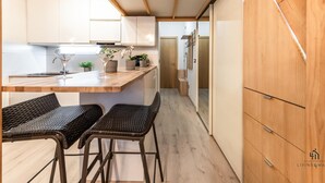 Une cuisine moderne avec des meubles en bois, un plan de travail en marbre et deux chaises en osier.