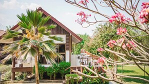 A two-story building with a sloped roof, surrounded by lush greenery and flowering trees. - Saitharn Iyara Resort (Sai Yok)
