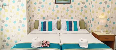 Habitación doble con dos camas, cada una con un corredor de cama color turquesa, ropa de cama blanca y almohadas color turquesa. En la pared, sobre las camas, hay una obra de arte floral enmarcada.