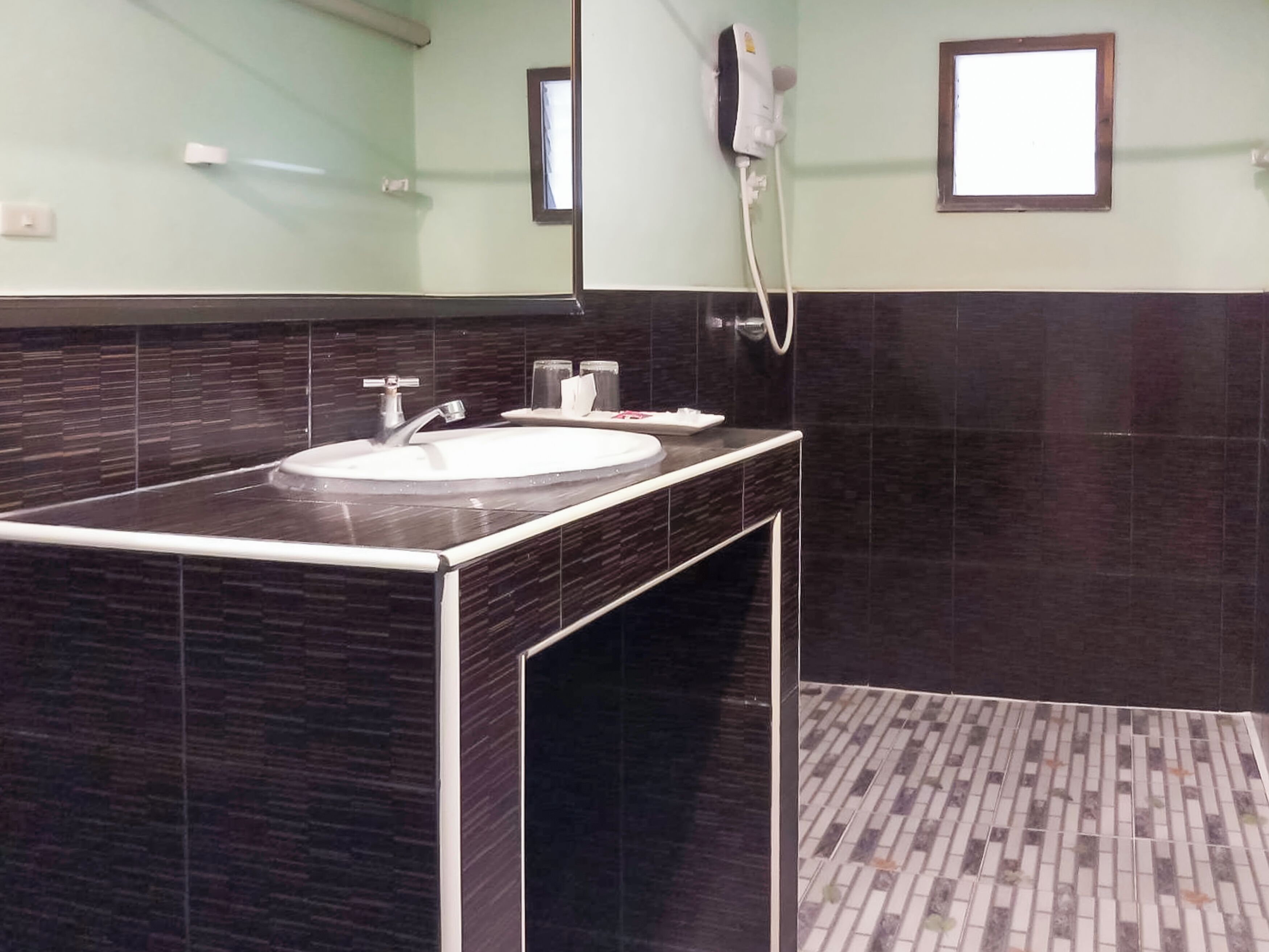 Un baño moderno con lavamanos de mármol oscuro, un espejo y un dispensador de toallas.