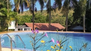 A swimming pool with a metal ladder, surrounded by tropical plants and palm trees. - Saitharn Iyara Resort (Sai Yok)