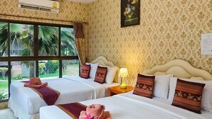 A hotel room with two beds, a window with a view of palm trees, and a lamp on the nightstand. - Saitharn Iyara Resort (Sai Yok)