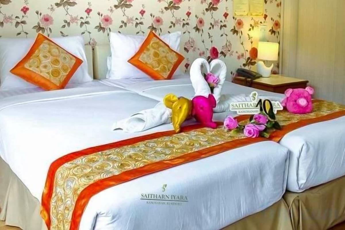 Una habitación de hotel con cama, almohadas, una decoración de toallas y un cartel sobre la cama.